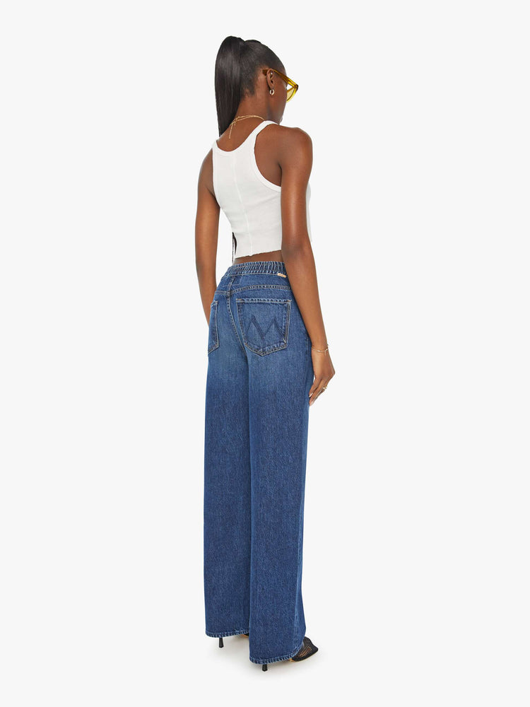 Back view of a woman in a dark blue wide-leg jean with a relaxed fit that's designed to sit on the hips with an elastic drawstring waistband, 32-inch inseam and a clean hem. 