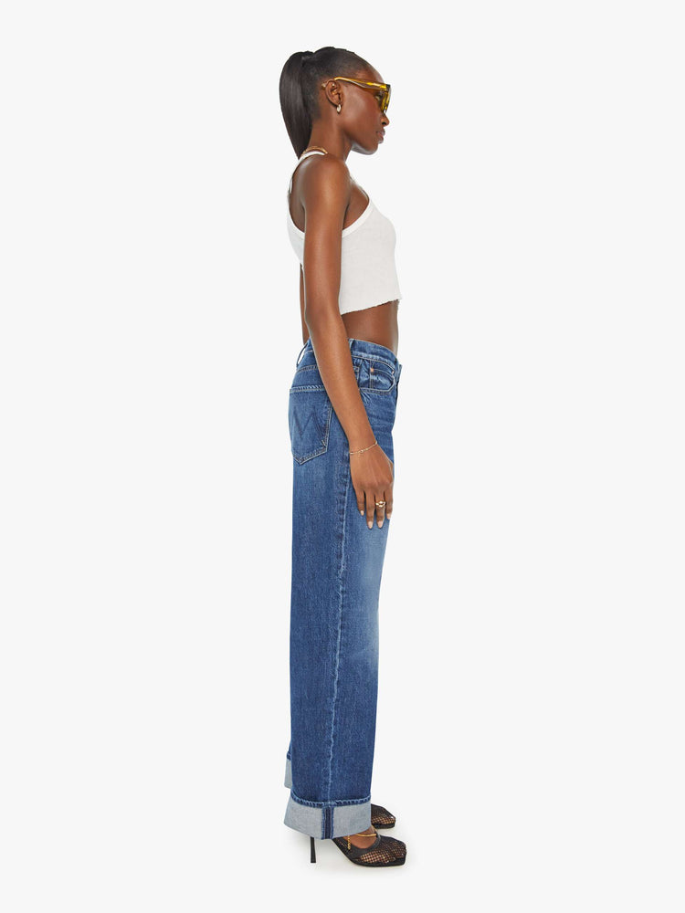 Side view of a woman in low rise dark blue straight-leg jeans with a cuffed hem.