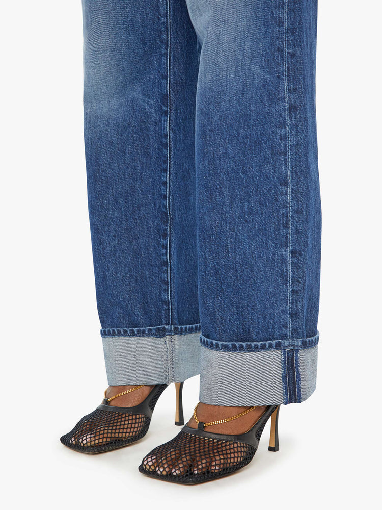 Close up hem view of a woman in low rise dark blue straight-leg jeans with a cuffed hem.