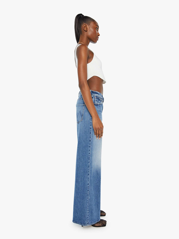 Side view of a woman in a mid-blue wash wide-leg jeans feature a high rise with a slightly dropped crotch, low-set back pockets, a slouchier fit designed to sit on the hips and a 31-inch inseam.