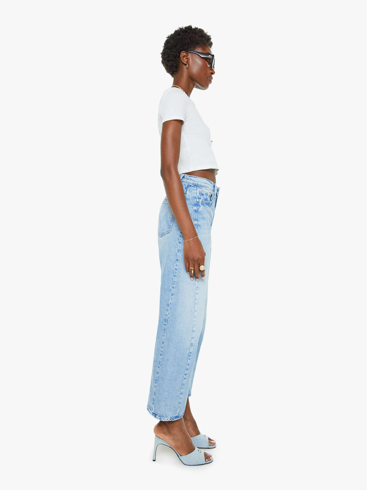 Side view of a woman super high-waisted jean with a wide, curved leg, an ankle-length inseam and a clean hem in a light blue wash.