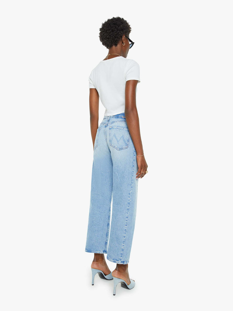 Back view of a woman super high-waisted jean with a wide, curved leg, an ankle-length inseam and a clean hem in a light blue wash.