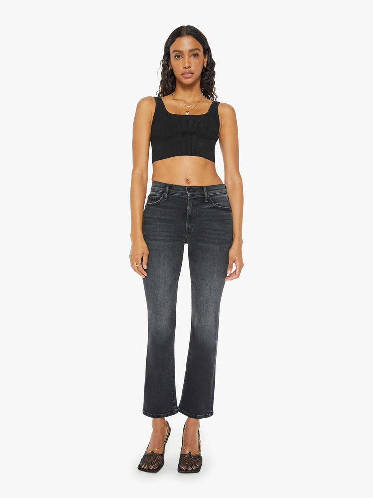 Front view of a woman in a black wash bootcut jeans with a mid rise and a 29.25-inch inseam with a clean hem.