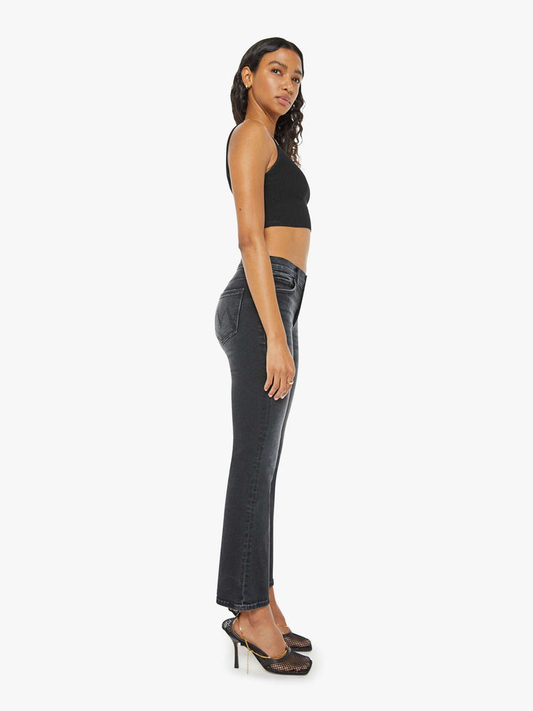 Side view of a woman in a black wash bootcut jeans with a mid rise and a 29.25-inch inseam with a clean hem.