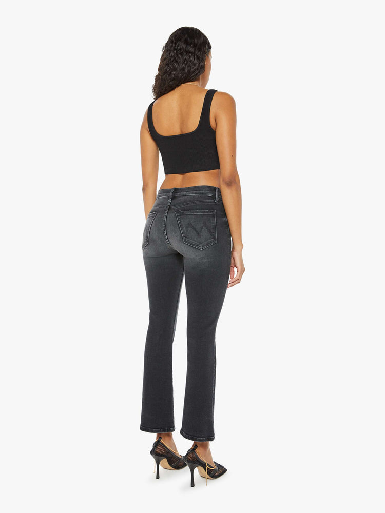 Back view of a woman in a black wash bootcut jeans with a mid rise and a 29.25-inch inseam with a clean hem.