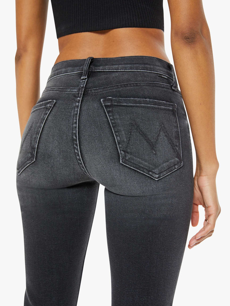 Back close up view of a woman in a black wash bootcut jeans with a mid rise and a 29.25-inch inseam with a clean hem.