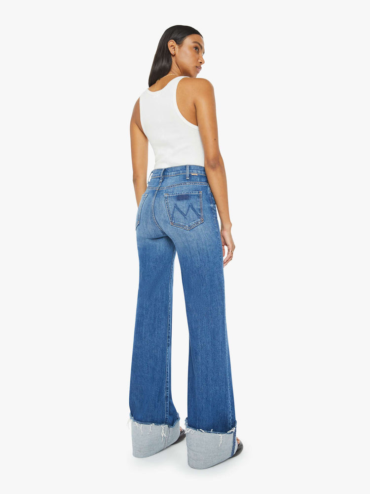 Back view of a woman wide leg jeans with a high rise, long 34-inch inseam and an oversized cuffed hem that's frayed in medium blue wash. 