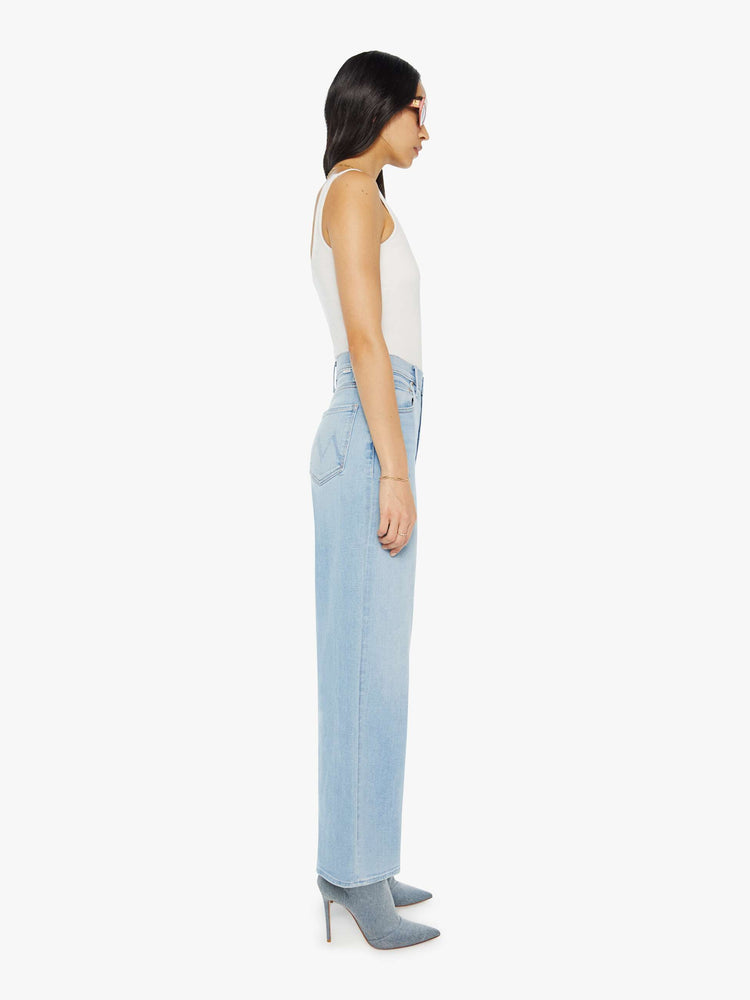 Side view of a woman Super high-rise jeans with a loose wide leg, zip fly and a 28.25-inch inseam with a clean hem in a light blue wash.