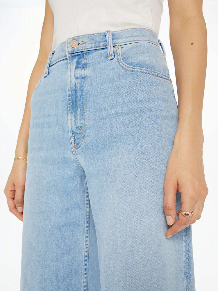 Close up waist view of a woman Super high-rise jeans with a loose wide leg, zip fly and a 28.25-inch inseam with a clean hem in a light blue wash.