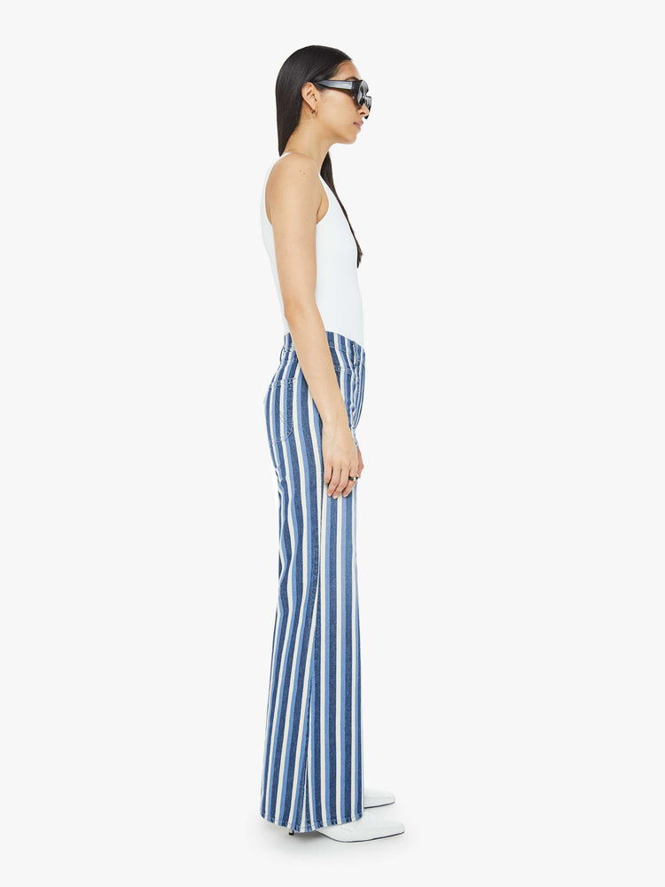 Side view of a woman in a flared,  wide-leg pants with patch pockets and a long 32-inch inseam with a clean hem in white and light blue stripes.