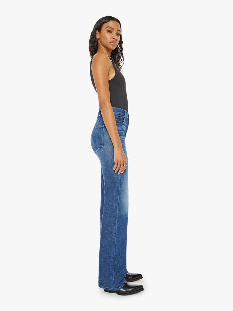 Side view of a woman med blue high-rise jeans with a wide straight leg, zip fly and a long 34-inch inseam with a clean hem.