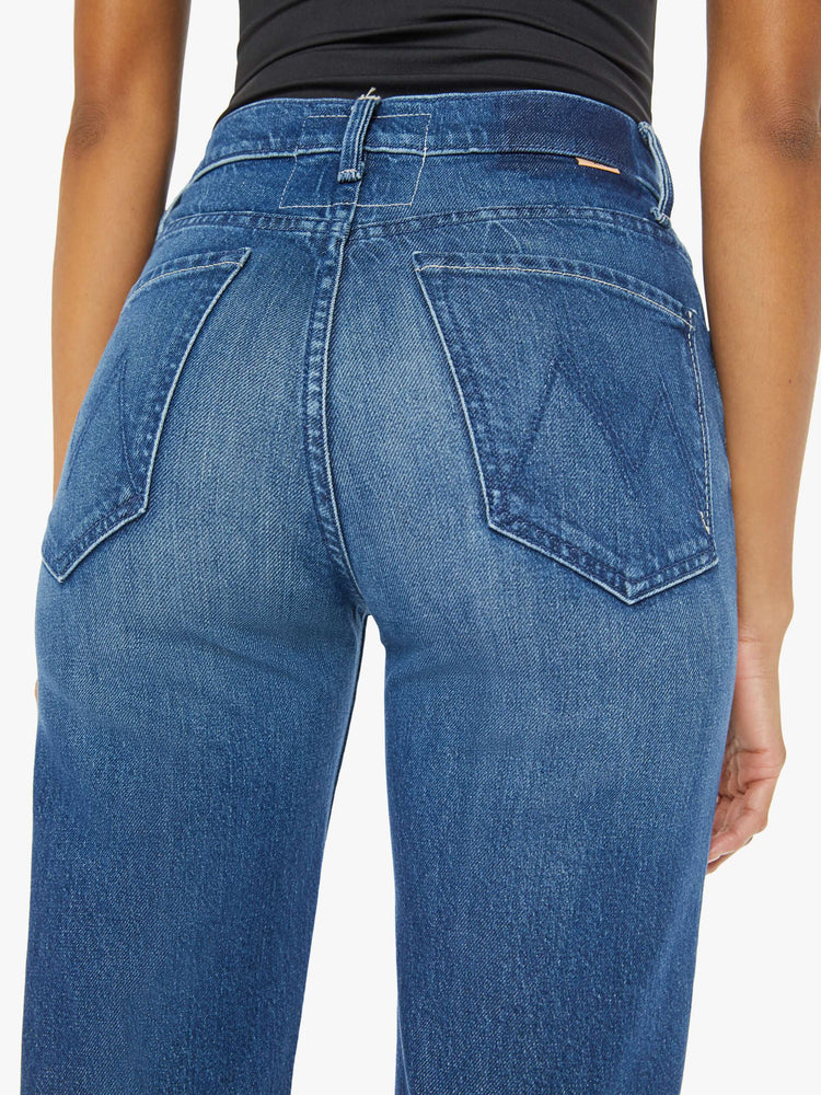 Back waist view of a woman med blue high-rise jeans with a wide straight leg, zip fly and a long 34-inch inseam with a clean hem.