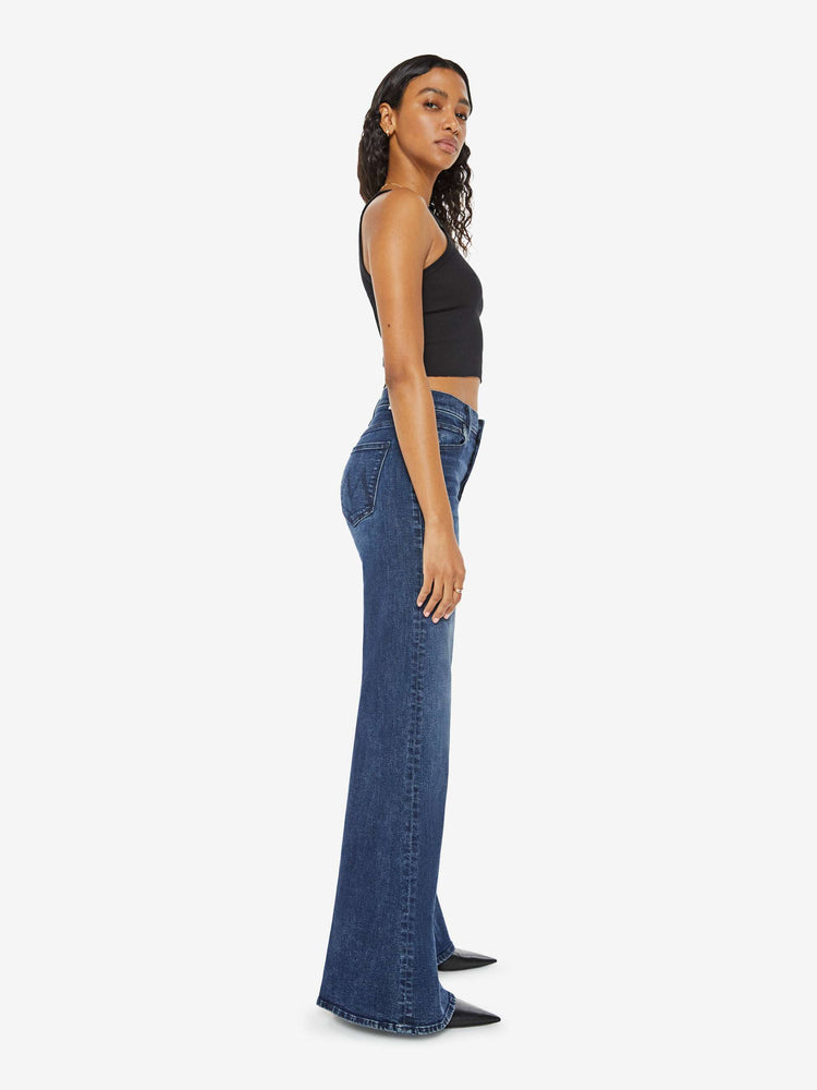 Side view of a dark blue high-waisted wide leg has a button fly, 32-inch inseam and clean hem.