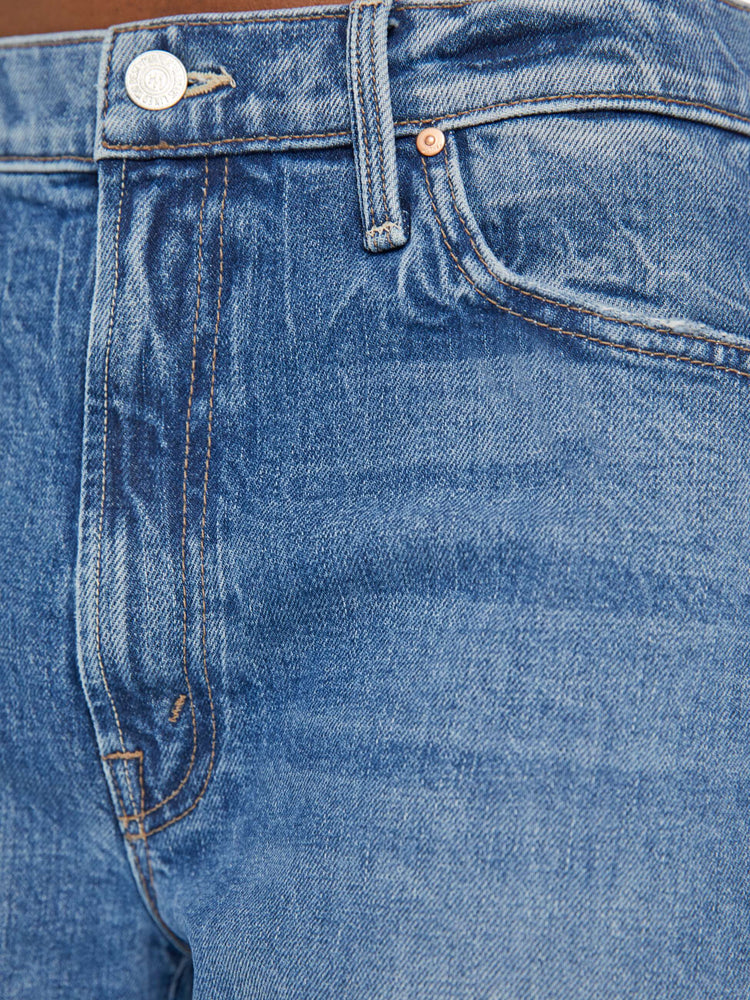 Close up swatch view of woman in a mid blue wash jean designed to sit lower on the hips with a loose straight leg and a 31-inch inseam with a clean cuffed hem.