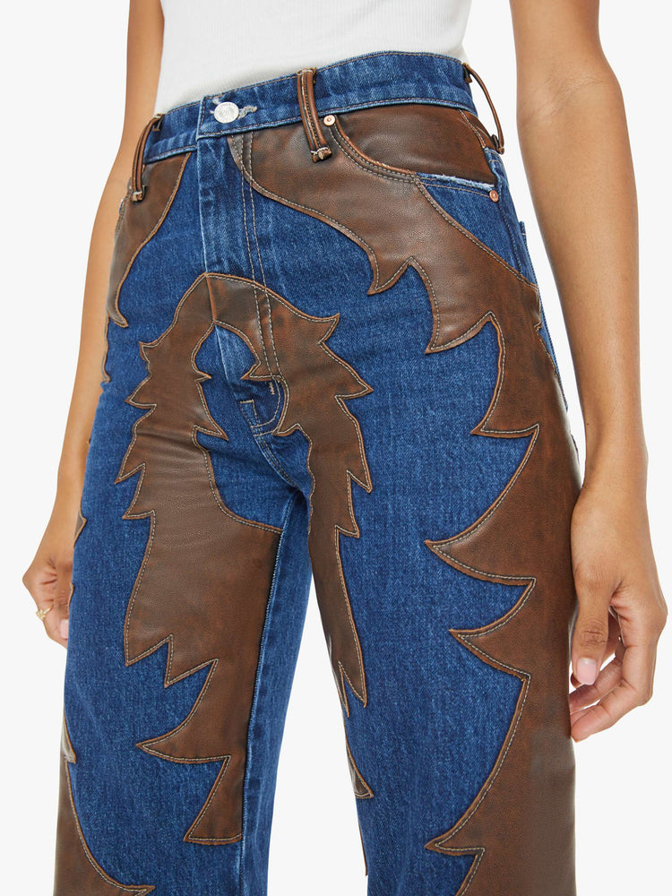 Close up  waist view of a woman super high-waisted bootcut jeans with a 34-inch inseam and clean hem in a dark blue wash with a faux leather applique.