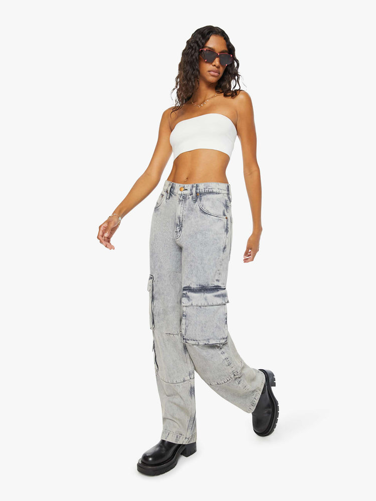 Angled view of a woman in acid-washed grey wide-leg pants feature a super high rise, long 31-inch inseam, cargo-inspired patch pockets and a loose, slightly baggy fit.