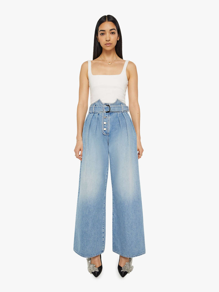 Front view of a light blue super high-waisted wide-leg jean features a belted waistband with pleats and angled details, an exposed button fly and a long 31-inch inseam with a clean hem.