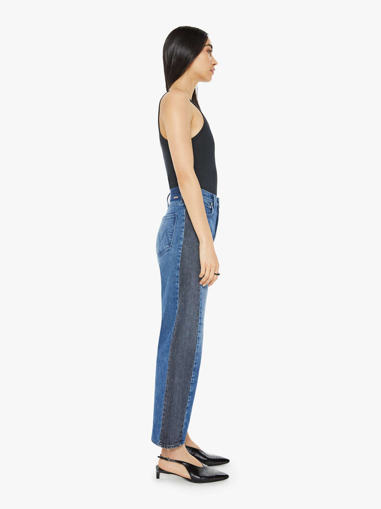 Side view of a woman in a black and blue super high-waisted jean with a wide, curved leg, a 26.25-inch inseam and a clean hem.