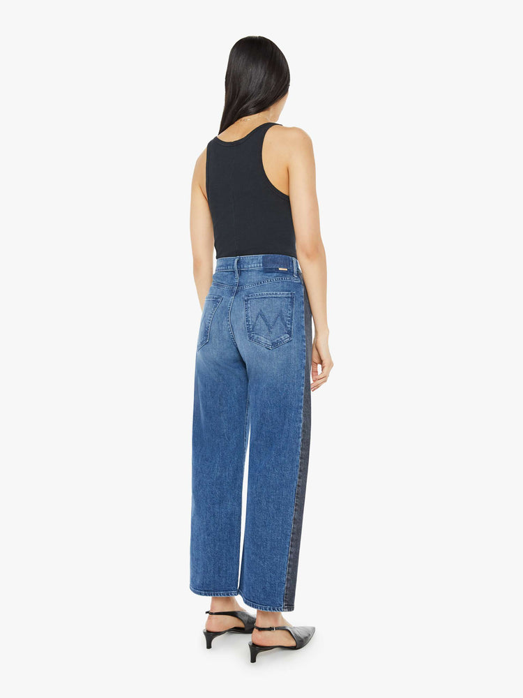 Back view of a woman in a black and blue super high-waisted jean with a wide, curved leg, a 26.25-inch inseam and a clean hem.