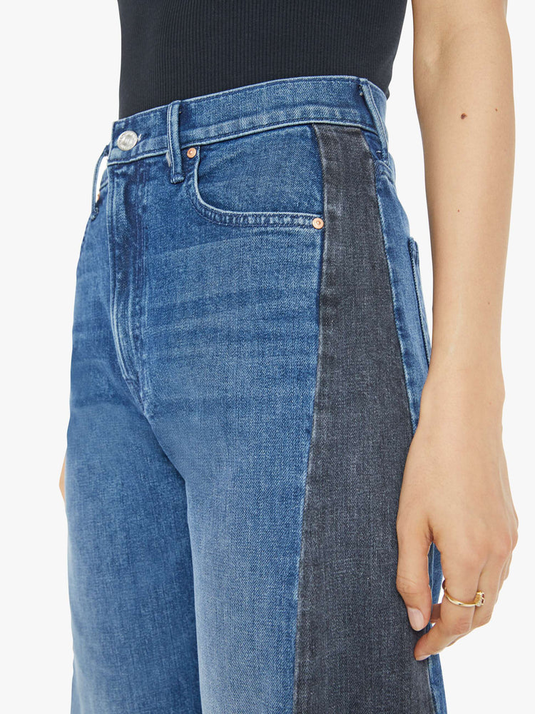 Waist close up view of a woman in a black and blue super high-waisted jean with a wide, curved leg, a 26.25-inch inseam and a clean hem.