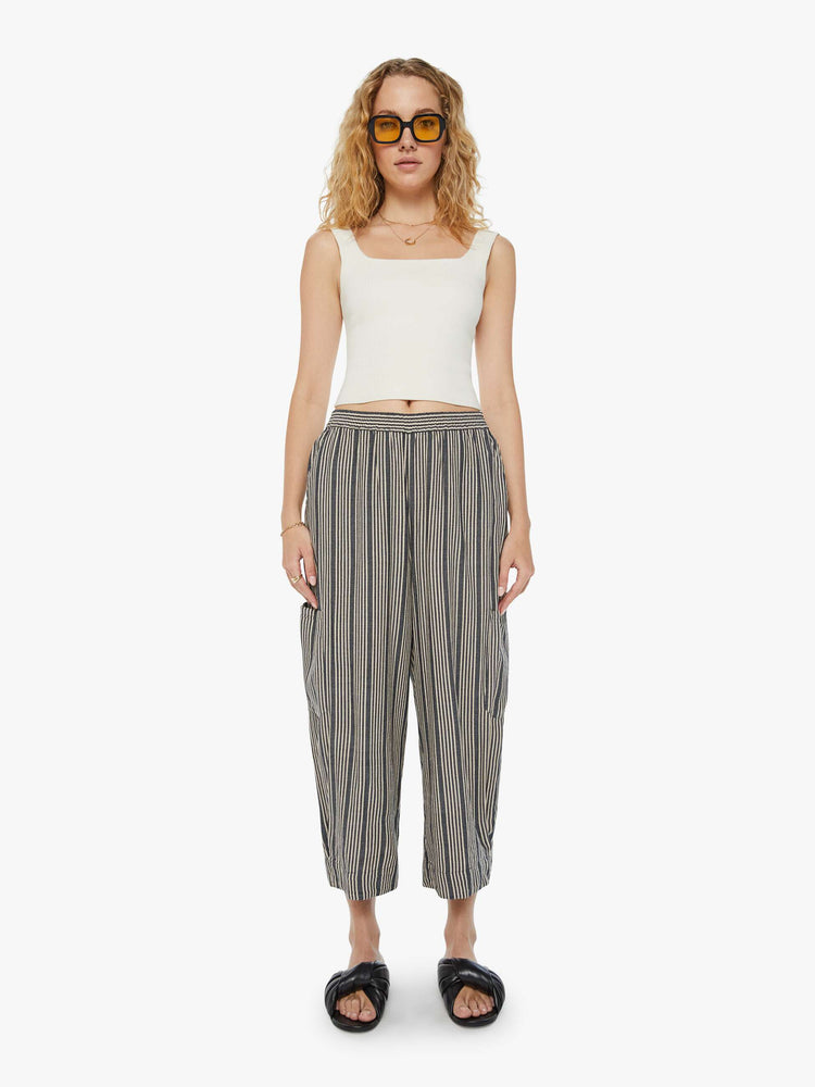 Front view of a woman cropped trousers with an elastic waistband, a tapered wide leg, cargo patch pockets in dark grey with a white stripe pattern.