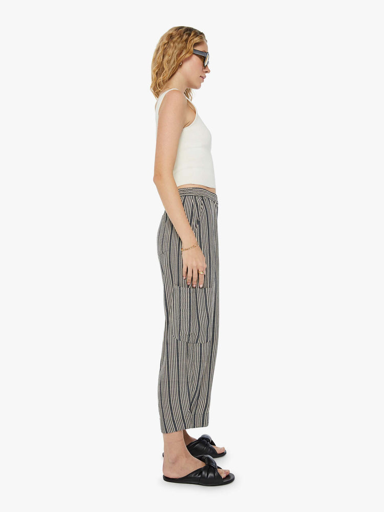 Side view of a woman cropped trousers with an elastic waistband, a tapered wide leg, cargo patch pockets in dark grey with a white stripe pattern.