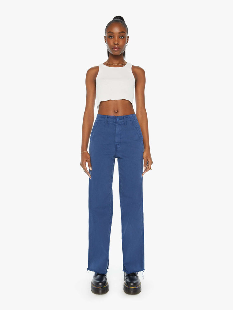 Front view of a blue pant super high-waisted pants with a loose straight leg, side slit pockets, long 32-inch inseam and a frayed hem.