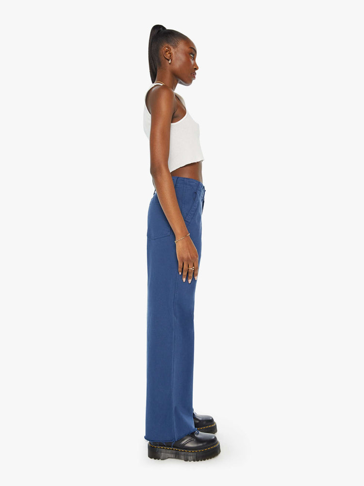 Side view of a blue pant super high-waisted pants with a loose straight leg, side slit pockets, long 32-inch inseam and a frayed hem.