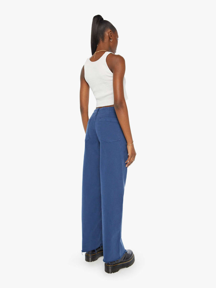 Back view of a blue pant super high-waisted pants with a loose straight leg, side slit pockets, long 32-inch inseam and a frayed hem.