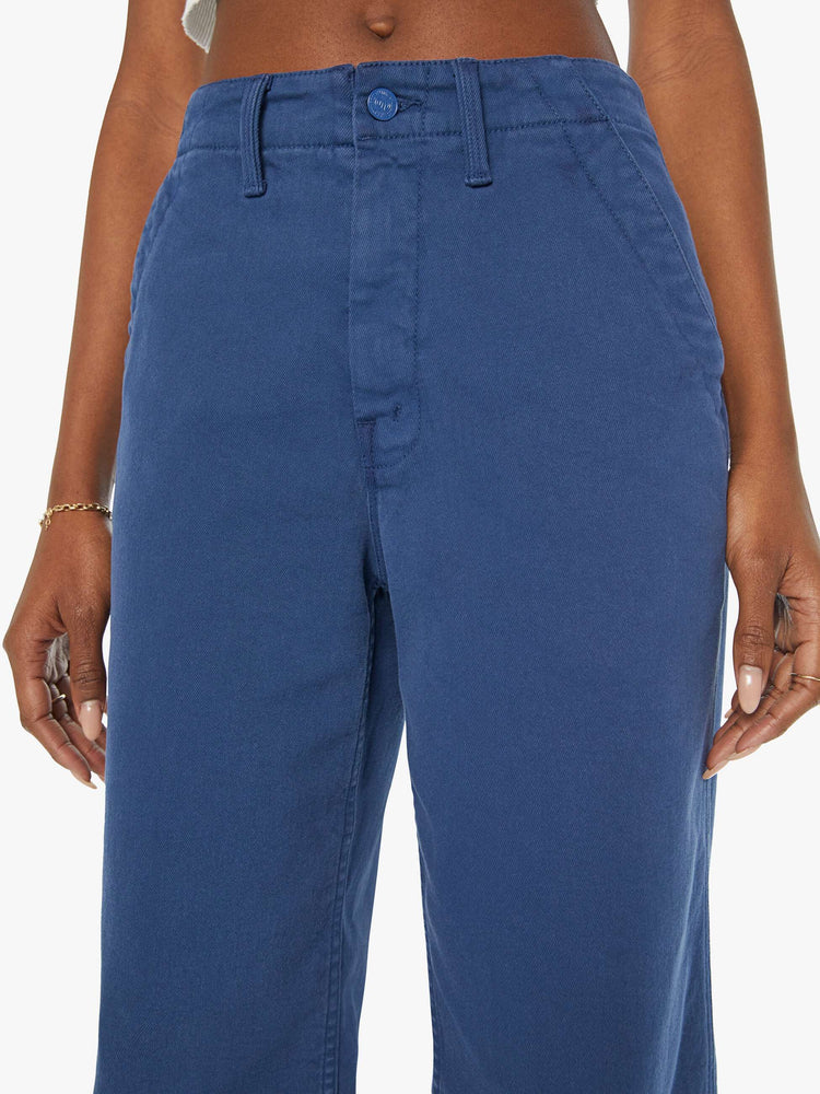 Close up view of a blue pant super high-waisted pants with a loose straight leg, side slit pockets, long 32-inch inseam and a frayed hem.