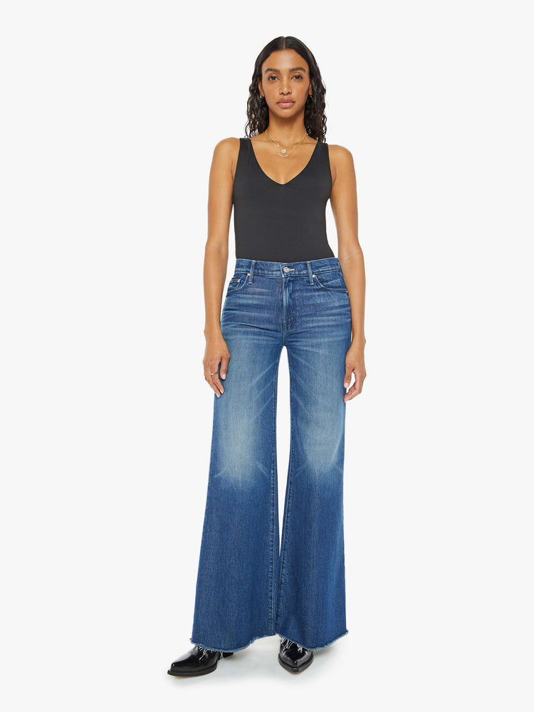 Front view of a med blue wash super wide-leg jeans with a high rise, a slouchy fit, flared leg and a long 32-inch inseam with a frayed hem.