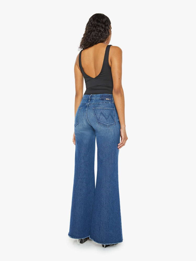 Back view of a med blue wash super wide-leg jeans with a high rise, a slouchy fit, flared leg and a long 32-inch inseam with a frayed hem.