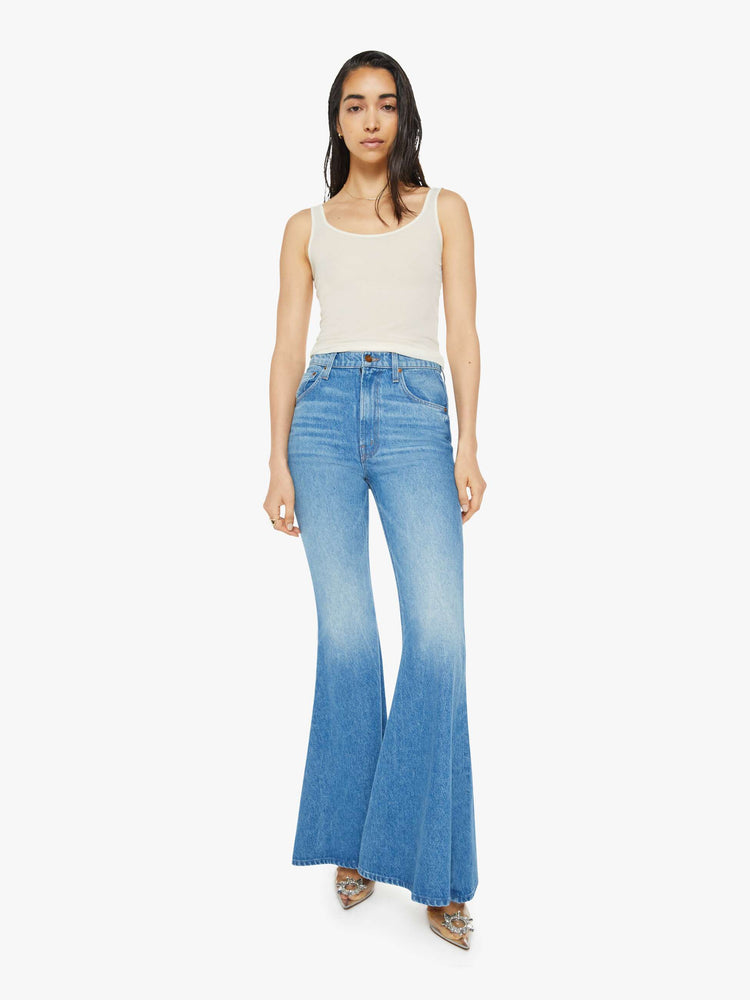 Front view of a woman in high-waisted light blue jeans have an extreme flare and a long 34-inch inseam with a clean hem. 