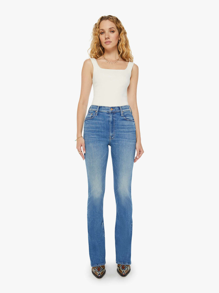 Front view of a woman high-waisted skinny-flare jeans with a slightly dropped crotch, long 34-inch inseam, slits at the heels and a clean hem in a mid blue wash.