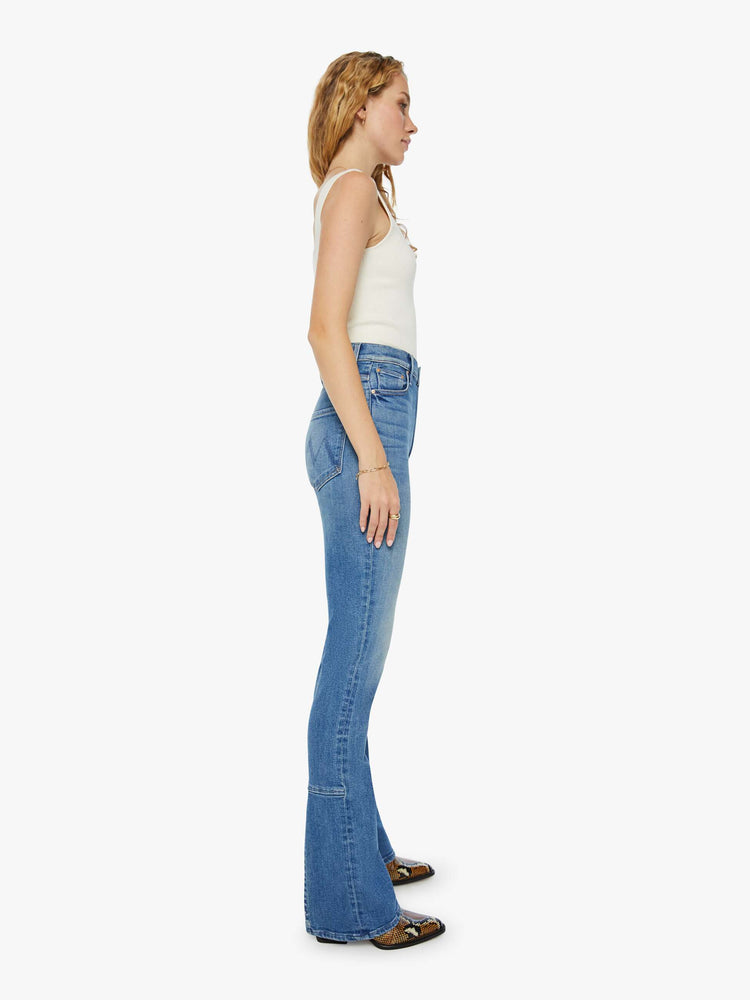 Side view of a woman high-waisted skinny-flare jeans with a slightly dropped crotch, long 34-inch inseam, slits at the heels and a clean hem in a mid blue wash.