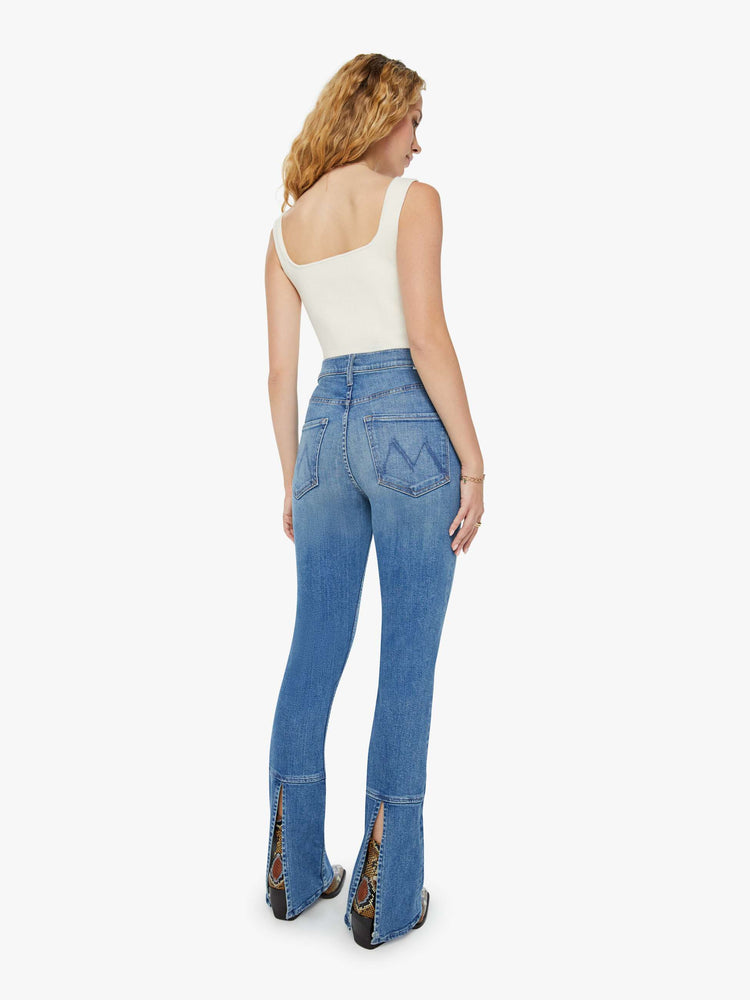 Back view of a woman high-waisted skinny-flare jeans with a slightly dropped crotch, long 34-inch inseam, slits at the heels and a clean hem in a mid blue wash.