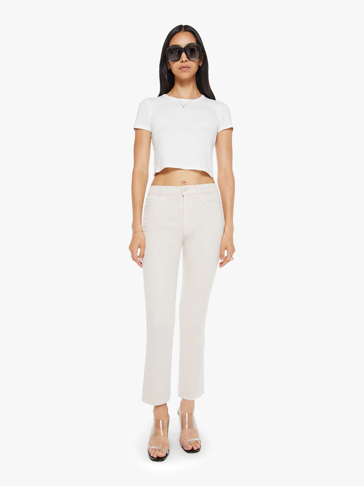 Front view of a woman in a off white cream color mid-rise pants with a flared leg and a 28.25-inch inseam with a clean hem. 