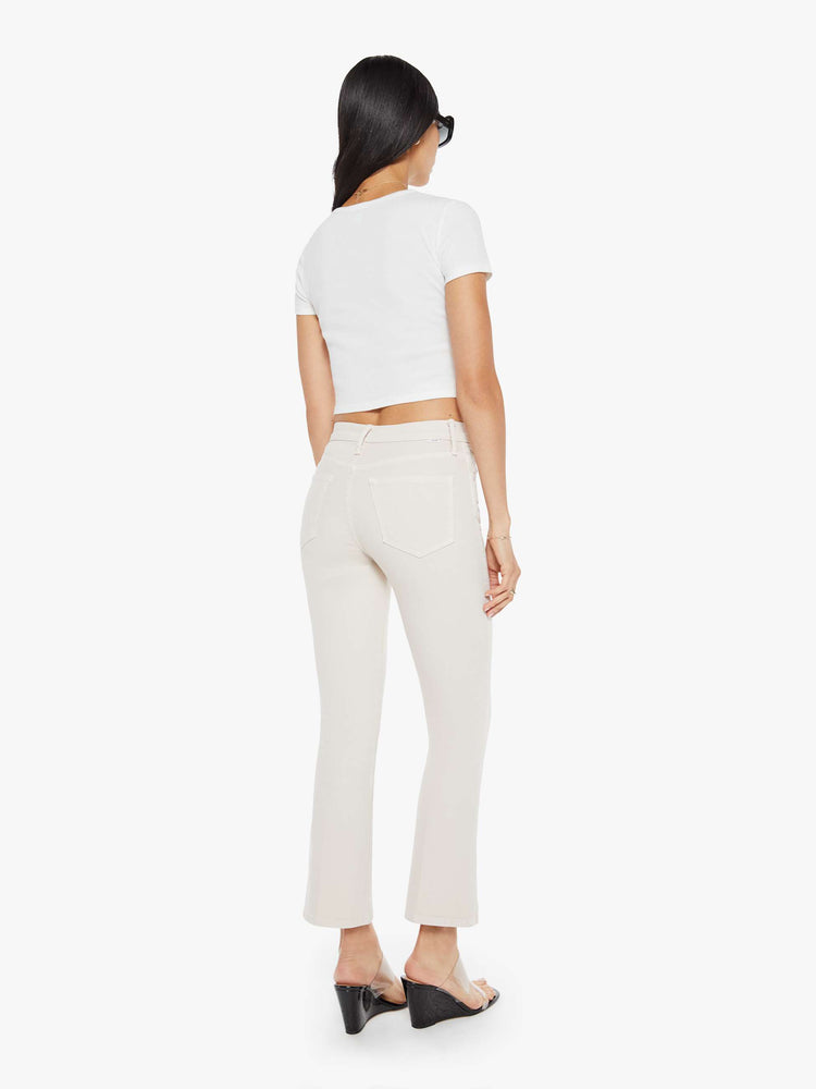 Back  view of a woman in a off white cream color mid-rise pants with a flared leg and a 28.25-inch inseam with a clean hem. 