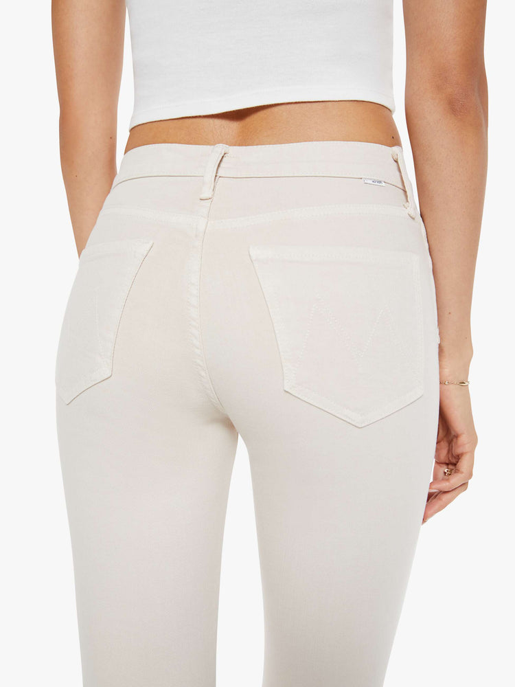 Back close up  view of a woman in a off white cream color mid-rise pants with a flared leg and a 28.25-inch inseam with a clean hem. 