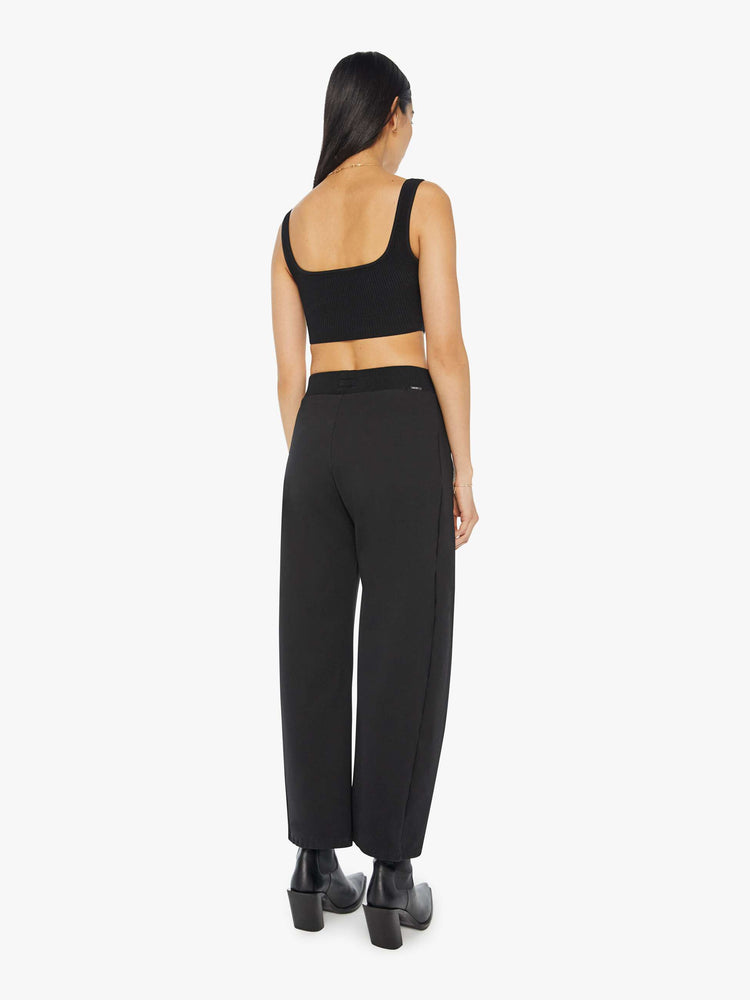 Back view of a woman in a black super high-waisted pants with a wide, curved leg, a thick elastic waistband, side slit pockets, a 28.25-inch inseam and a clean hem.