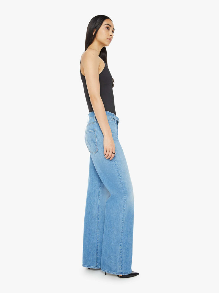 Side view of a woman in mid blue wash high-rise, straight-leg jeans have a foldover waistband, long 32-inch inseam and a loose fit. 