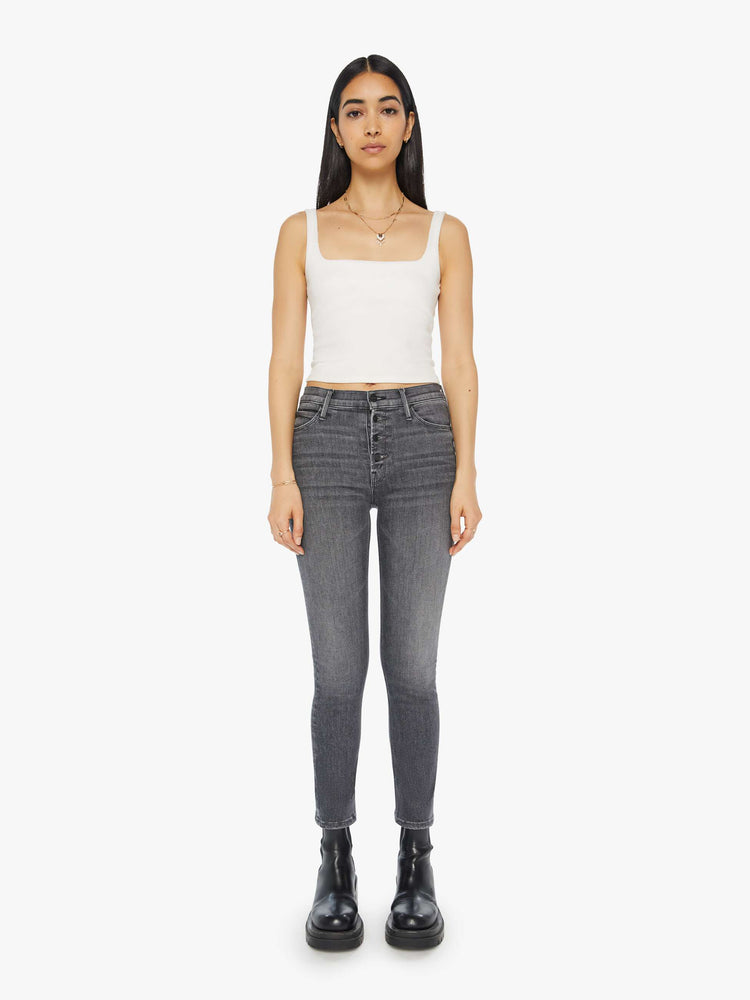 Front view of a woman in a dark grey mid rise straight leg jean with an exposed button fly and an ankle length inseam.