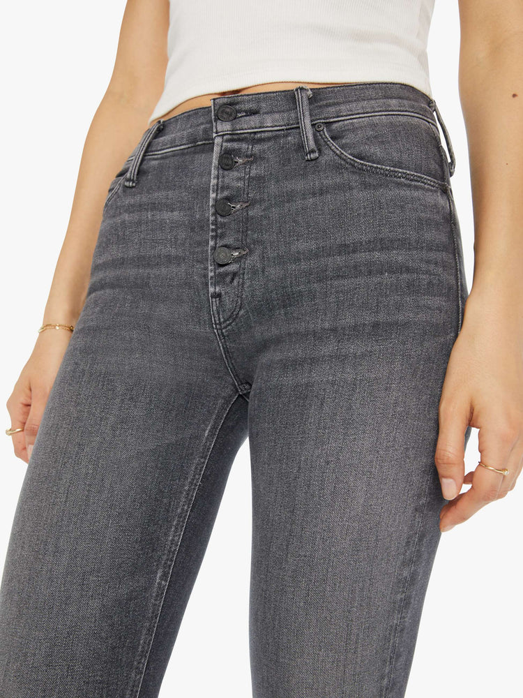 Close up view of a woman in a dark grey mid rise straight leg jean with an exposed button fly and an ankle length inseam.