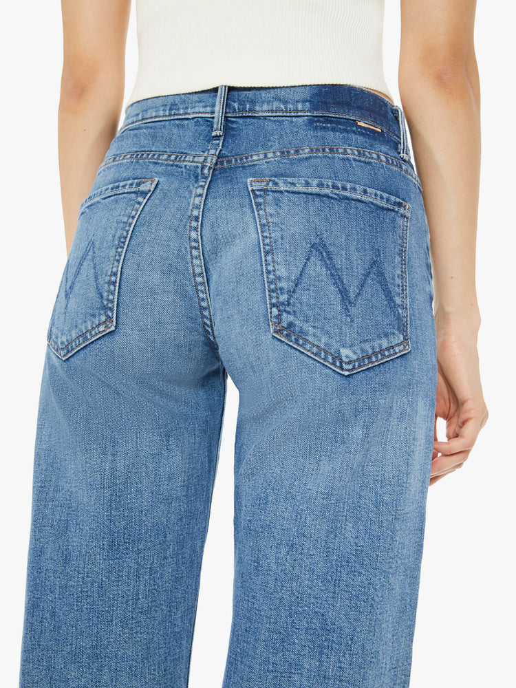 Back waist close up view of a med blue mid-rise jeans with a loose fit, wide leg and ankle-length inseam with a clean hem.