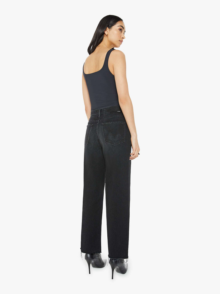 Back view of a woman in black  straight-leg jeans have an ankle-length inseam and a frayed hem. 