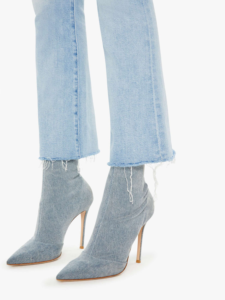 Detailed view of a woman in light blue high-rise flare with an ankle length raw hem.