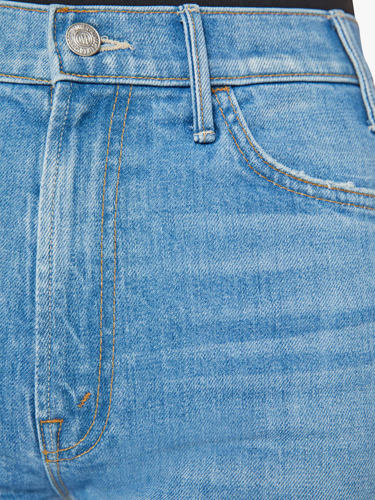 Swatch view of a woman in a mid blue wash high-rise bootcut has an ankle-length inseam and a raw hem.