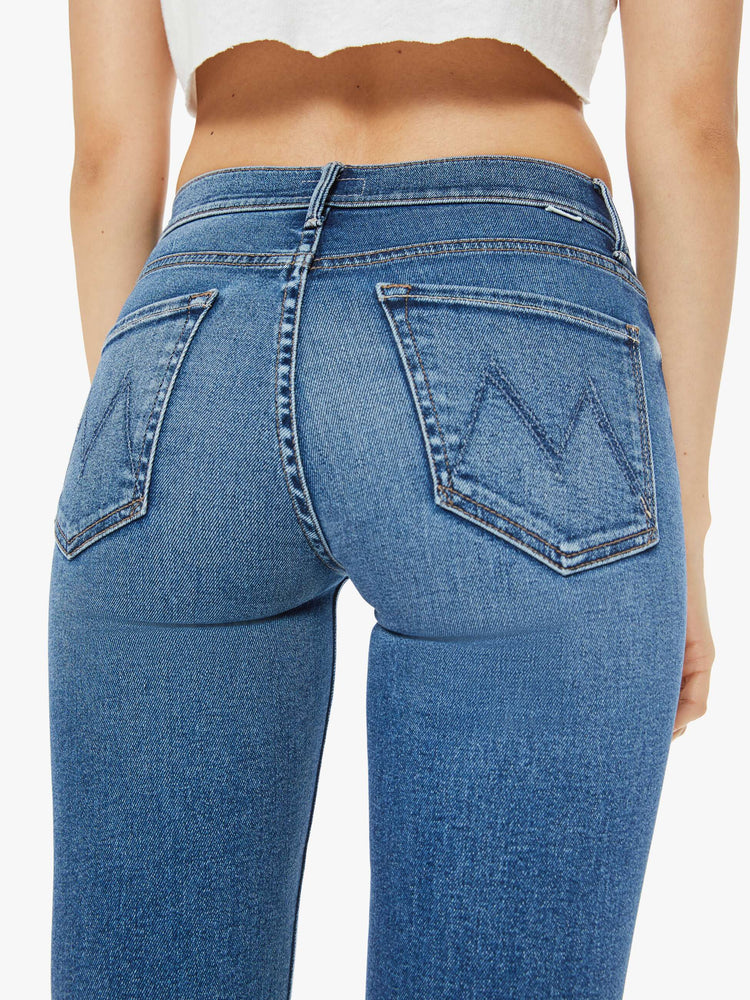 Back close view of a woman mid blue  mid-rise straight leg with a 28.25-inch inseam and a frayed hem. 