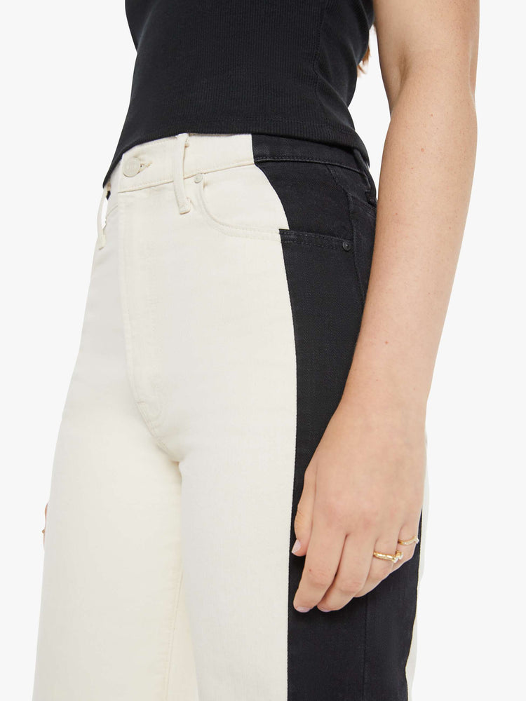 Close up view of a woman super high-waisted pants with a loose fit, wide leg and a long 34-inch inseam with a clean hem in a cream color and a black stripe down the outer seam.