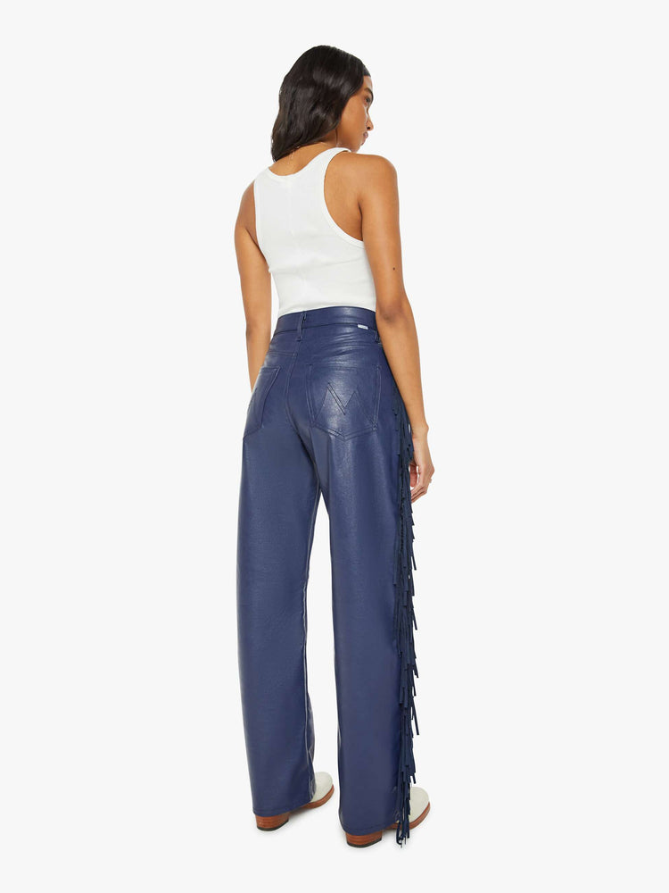 Back view of a woman in a super high-waisted pant with a wide, curved leg, a 32-inch inseam and a clean hem in a navy faux leather with fringe down the leg.